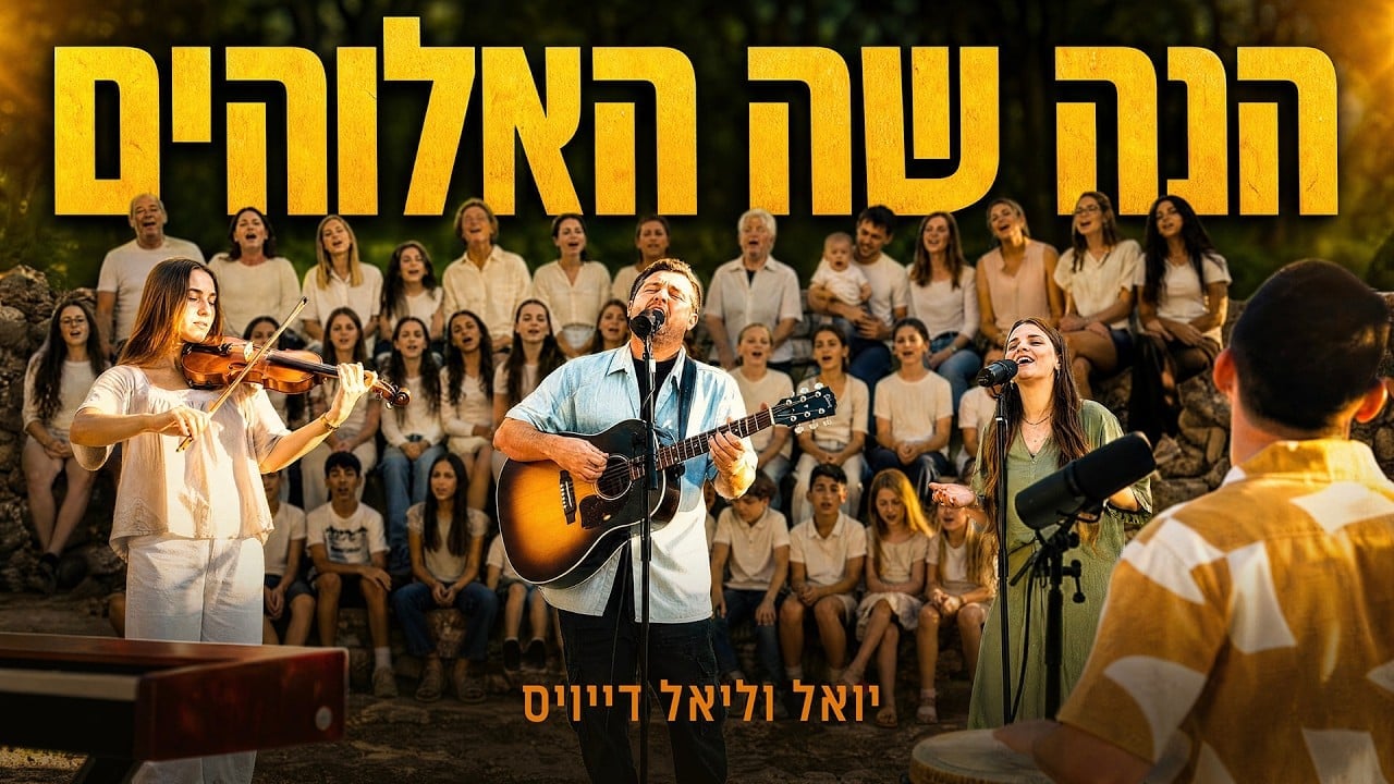 Outdoor choir performance with a guitarist and two lead vocalists in front of a white-clad chorus and seated audience; large Hebrew banner text above.